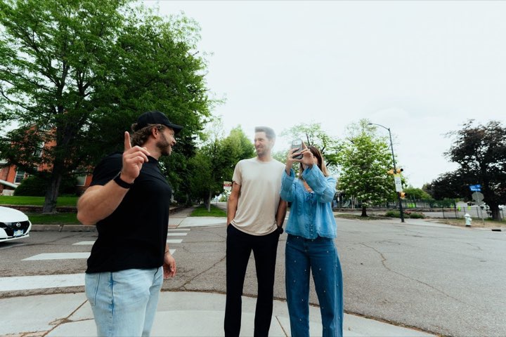 Three people on the street corner looking up at the new building, one pointing