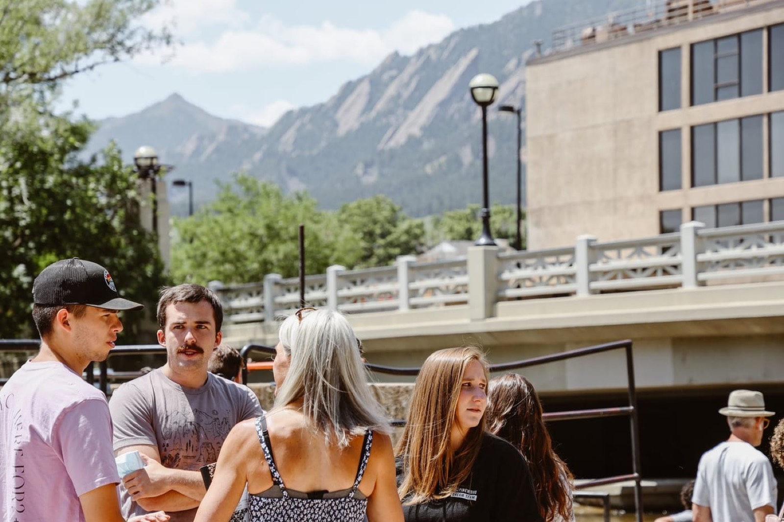 Friends talking by Boulder Creek with the Flatirons behind