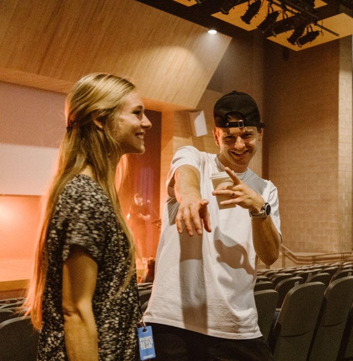 Two people laughing in the auditorium aisle