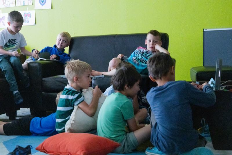 A group of boys on a couch and floor cushions in a bright green room
