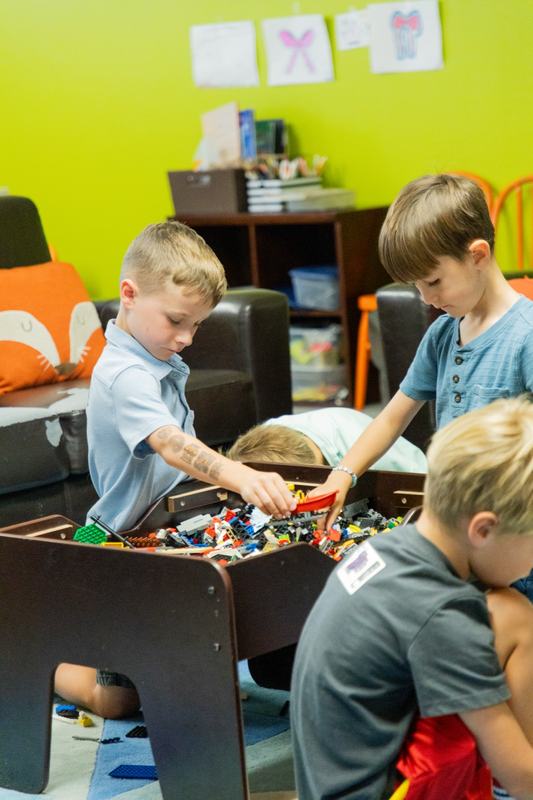 Three boys digging through a table full of building bricks