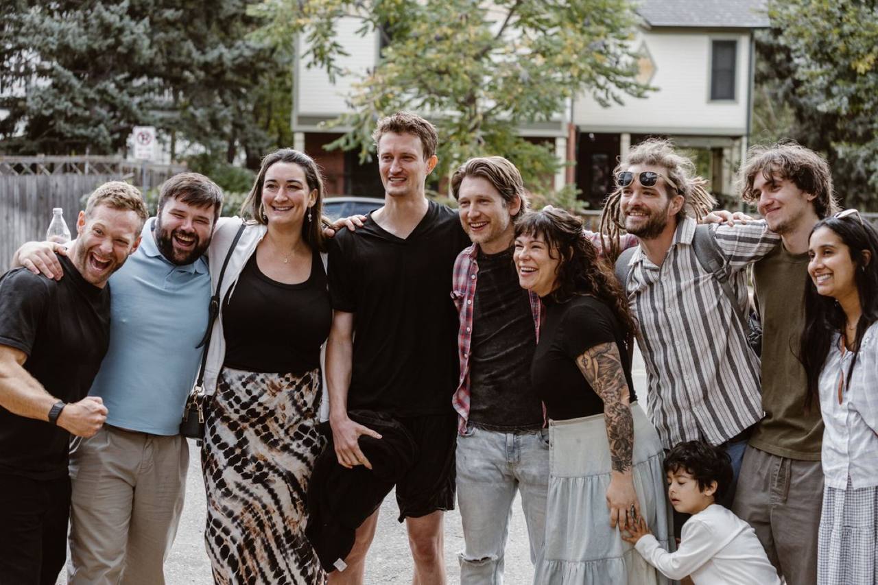 A group of friends laughing together for a photo outside a house