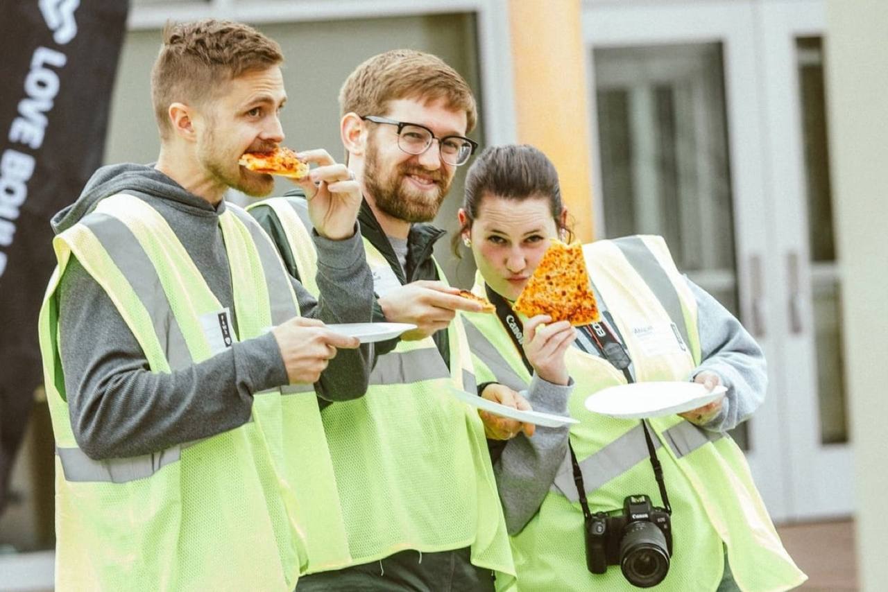 Volunteers in yellow safety vests grabbing slices of pizza