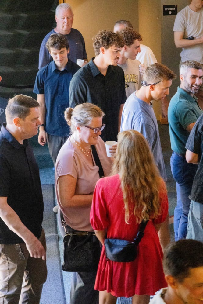 People standing close together in a crowded line after a service, one woman holding a coffee cup