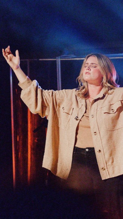 Worship leader with hand raised under stage light